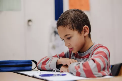 Un enfant fait ses devoirs à l'école. 