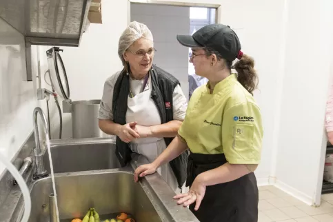 Une jeune fille et une aide cuisine en train d'échanger 